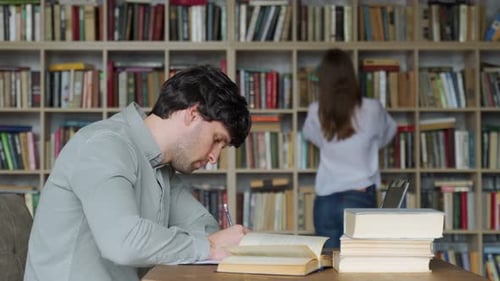 Estudiante masculino preparando el examen y aprendiendo lecciones en la biblioteca