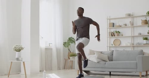 Young African American Guy Energetically Jogging in Place at Home, Domestic Cardio Training