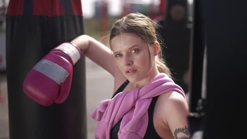 Woman Boxer Leaning Against Punching Bag Outdoors