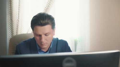 Stressed Man Working at Computer Drinks Water