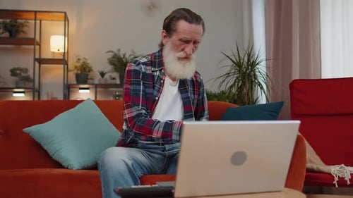 Senior Man Using Laptop and Tablet at Home