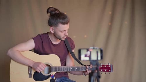 Young Adult Man Playing Acoustic Guitar at Home