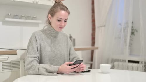 Young Woman Using Phone at Kitchen Table