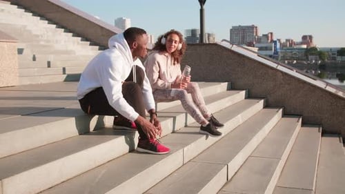 Fit Man Tying Shoes, Woman Listening to Music
