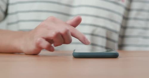 Finger Tapping on Smartphone Device at Table