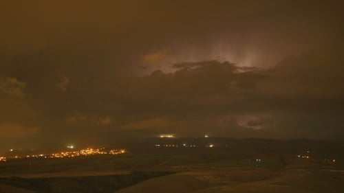 Lightning Flashes Over Distant Town at Night