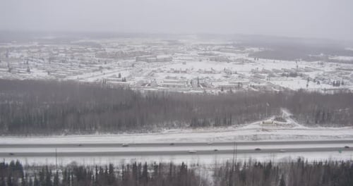 Aerial helicopter through snowy white hilltops over valley, drone footage