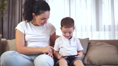 Woman and Child Using Tablet Together on Couch