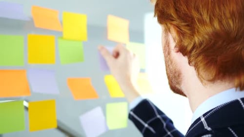 Arbeiten an Haftnotizen auf Glas im Büro, Rückansicht