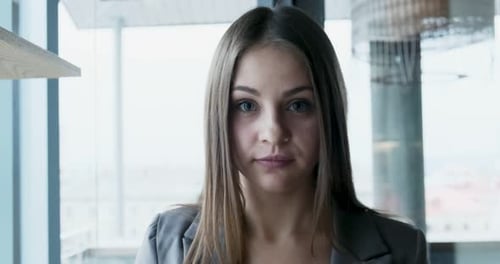 Portrait of Young Attractive Female Who Looking at the Camera on the Office Near Window. Cheerfully