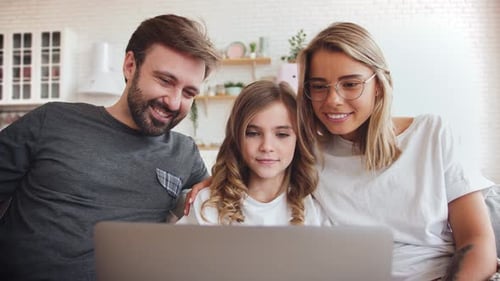 Family of Three Watching Laptop Together on Couch