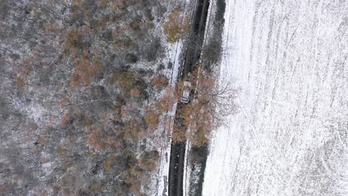 Aerial top view of car driving on snow countryside road - Aerial video of win