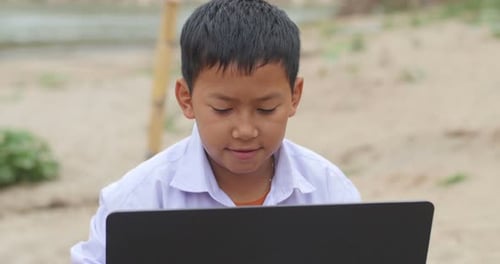 Boy Using Laptop in Rural Field