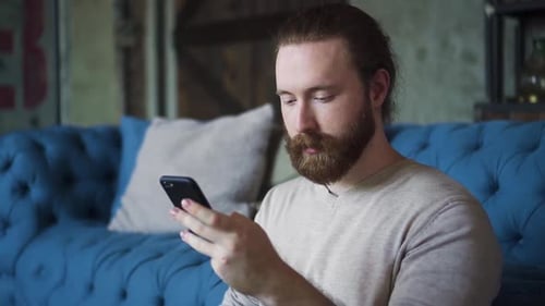 Man Using Smartphone While Sitting on Couch
