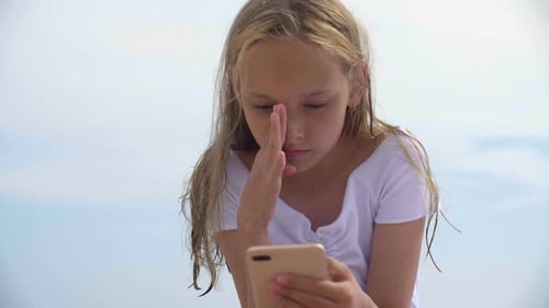 Girl Using Smartphone on Beach During the Day