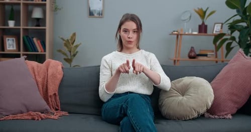 Young Woman Gesturing on Sofa in Living Room
