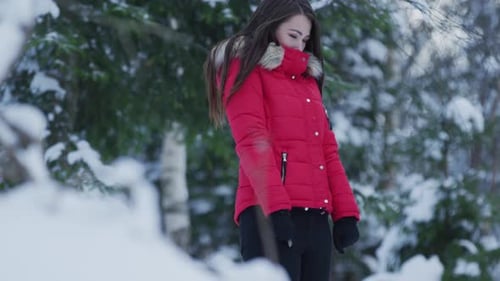 Woman in Red Coat Stands in Snowy Forest
