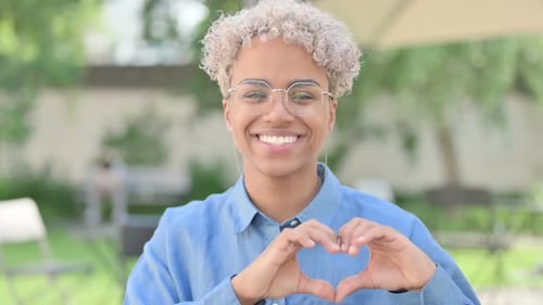 Smiling Young Adult Makes Heart Shape With Hands
