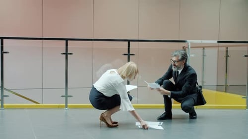 Des employés de bureau matures se cognent accidentellement dans un hall se serrant la main en parlant