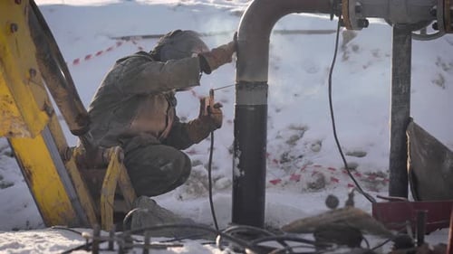 Worker Produces Pipe Welding on the Street. In Winter, at Low Temperatures