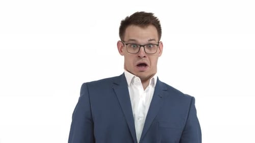 Hübscher, lustiger Geschäftsmann in blauem Anzug und Brille, der schockiert aussieht, den Kiefer herunterfallen und erschrocken nach hinten neigen