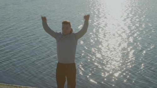 Man Athlete Is Warming Up Near Lake