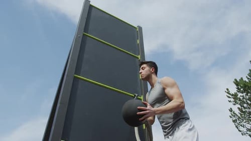Athletic Man Training with Medicine Ball on Rope