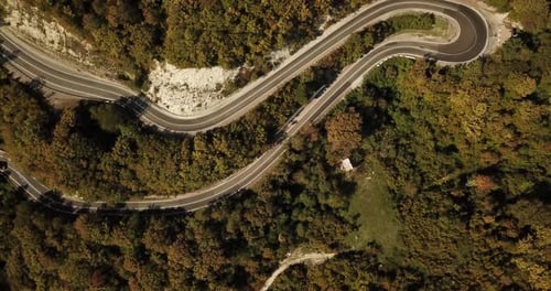 Aerial View of Car Driving Along The Winding Mountain Pass Road Through The Forest Trees. Autumn