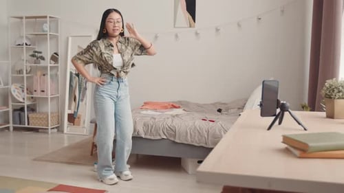 Adolescente asiática grabando Vídeo tutorial de baile en el teléfono inteligente en casa