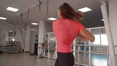 Young Woman Stretching and Rotating in Bright Gymnasium