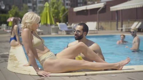 People Relaxing by a Swimming Pool in Summer