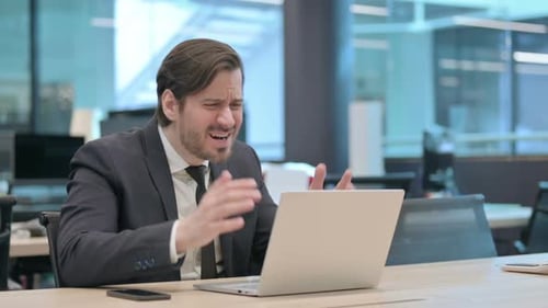 Frustrated Man Working on Laptop in Modern Office