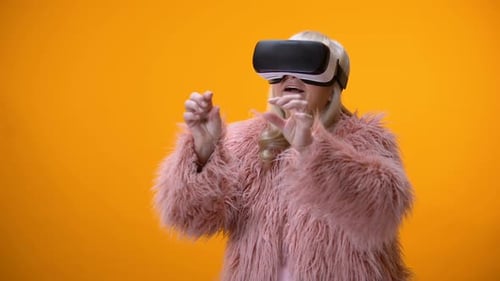 Senior Woman Wearing VR Headset with Orange Backdrop