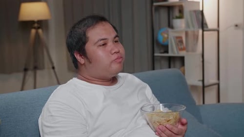 Young Adult Eating Chips on the Sofa