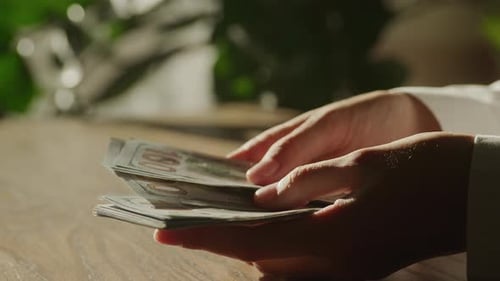 Handheld Close Up of Caucasian Woman Hands Counting Money in 100 Dollar Bill Banknote