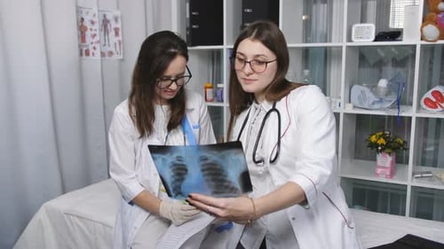 Two Young Doctors Examine X-Ray in Hospital