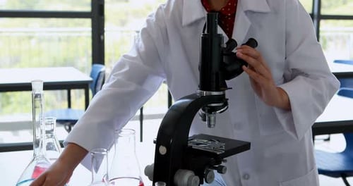 Young Adult Examining Sample Through Microscope in Lab