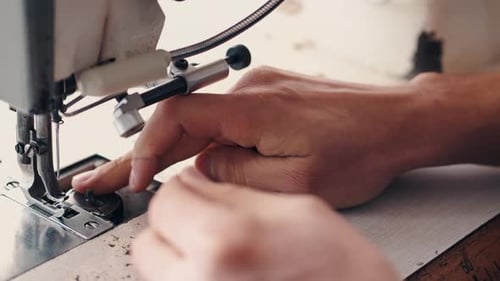 Hands Guiding Fabric Through Sewing Machine