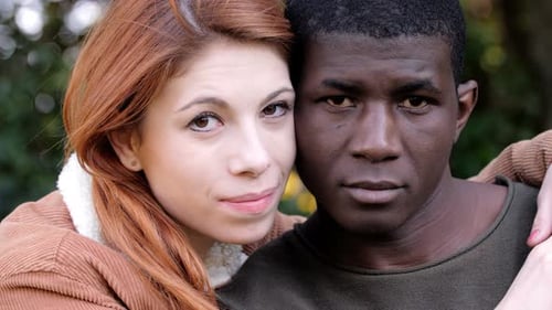Multiethnic love. Young attractive mixed couple in park looking at camera