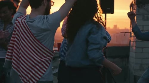 Friends Dancing at Rooftop Party at Sunset