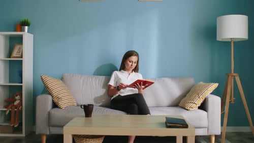Woman Reads a Book on Couch in Living Room