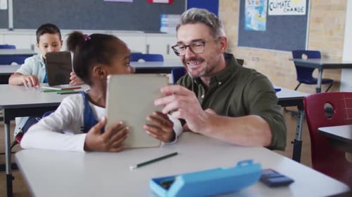Teacher Helping Student with Tablet in Classroom