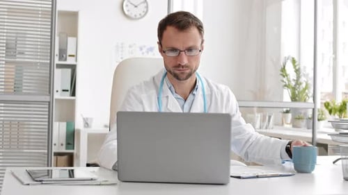 Doctor Working on Laptop at Bright Office Desk
