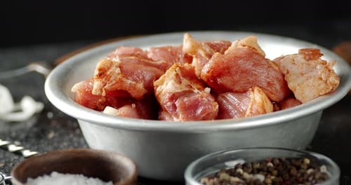Bowl with Raw Pork Kebab with Spices Slowly Rotating.