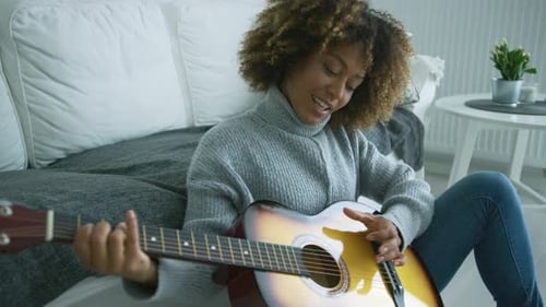 Woman Plays Guitar on Floor in Bright Room