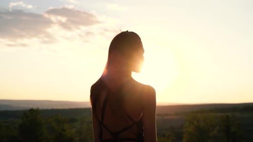 Woman Silhouetted Against Setting Sun in Nature