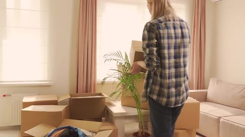 Woman Stacks Boxes in Bright Living Room
