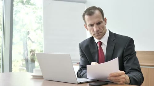 Geschäftsmann liest Dokumente und Papierkram