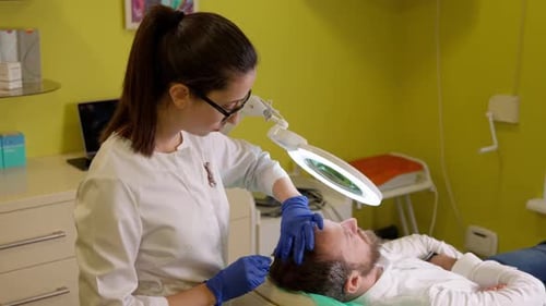 Woman Examines Man's Scalp with Magnifying Glass