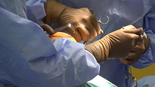 Surgeons Suturing Patient's Arm During Operation